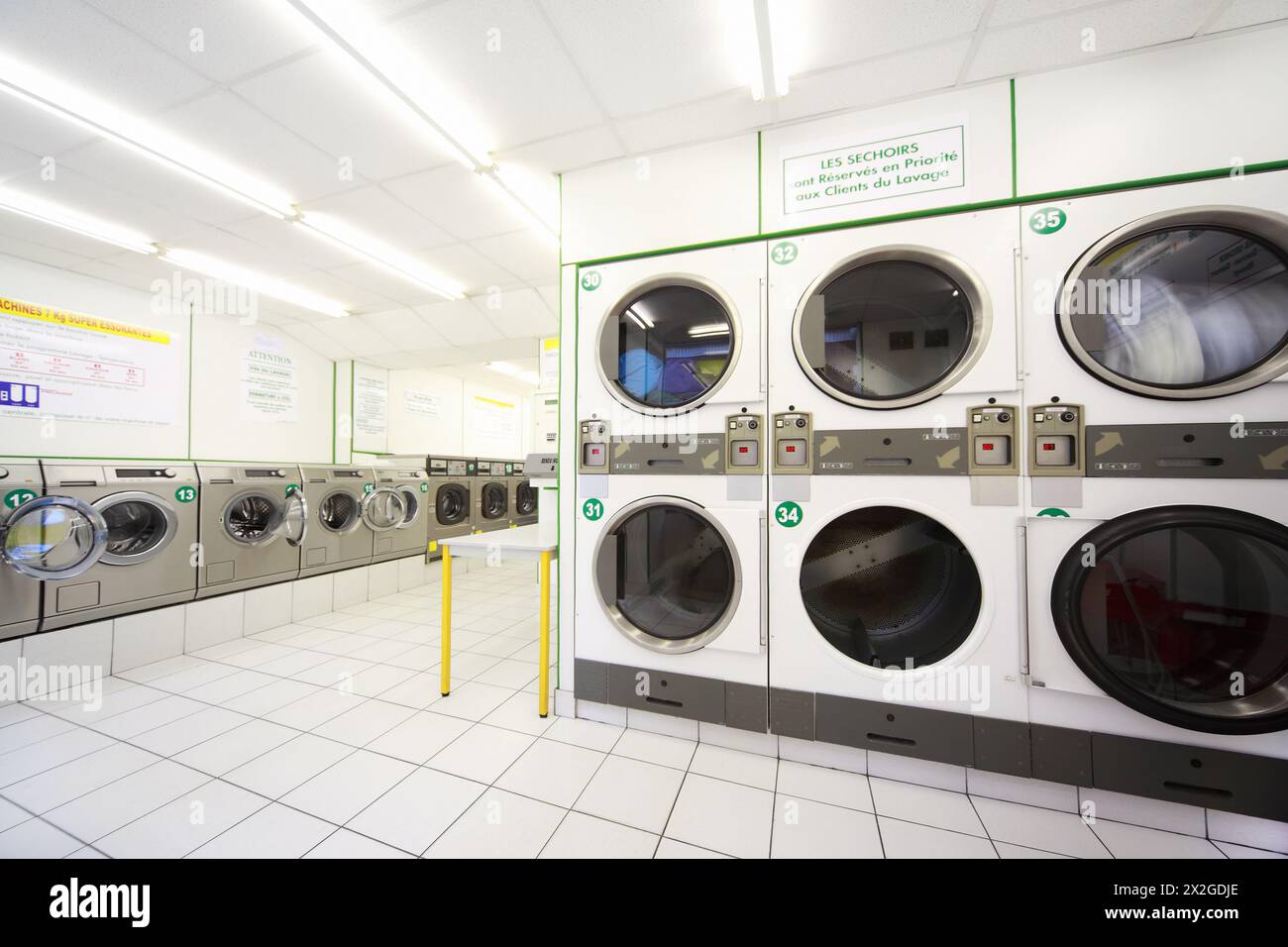 number of washing machines in empty public laundry, instructions on walls Stock Photo
