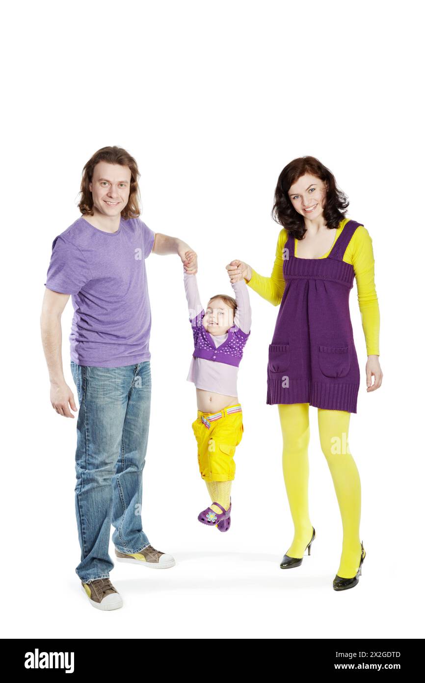 Father and mother swing by hands their little daughter, everybody smiles. Stock Photo