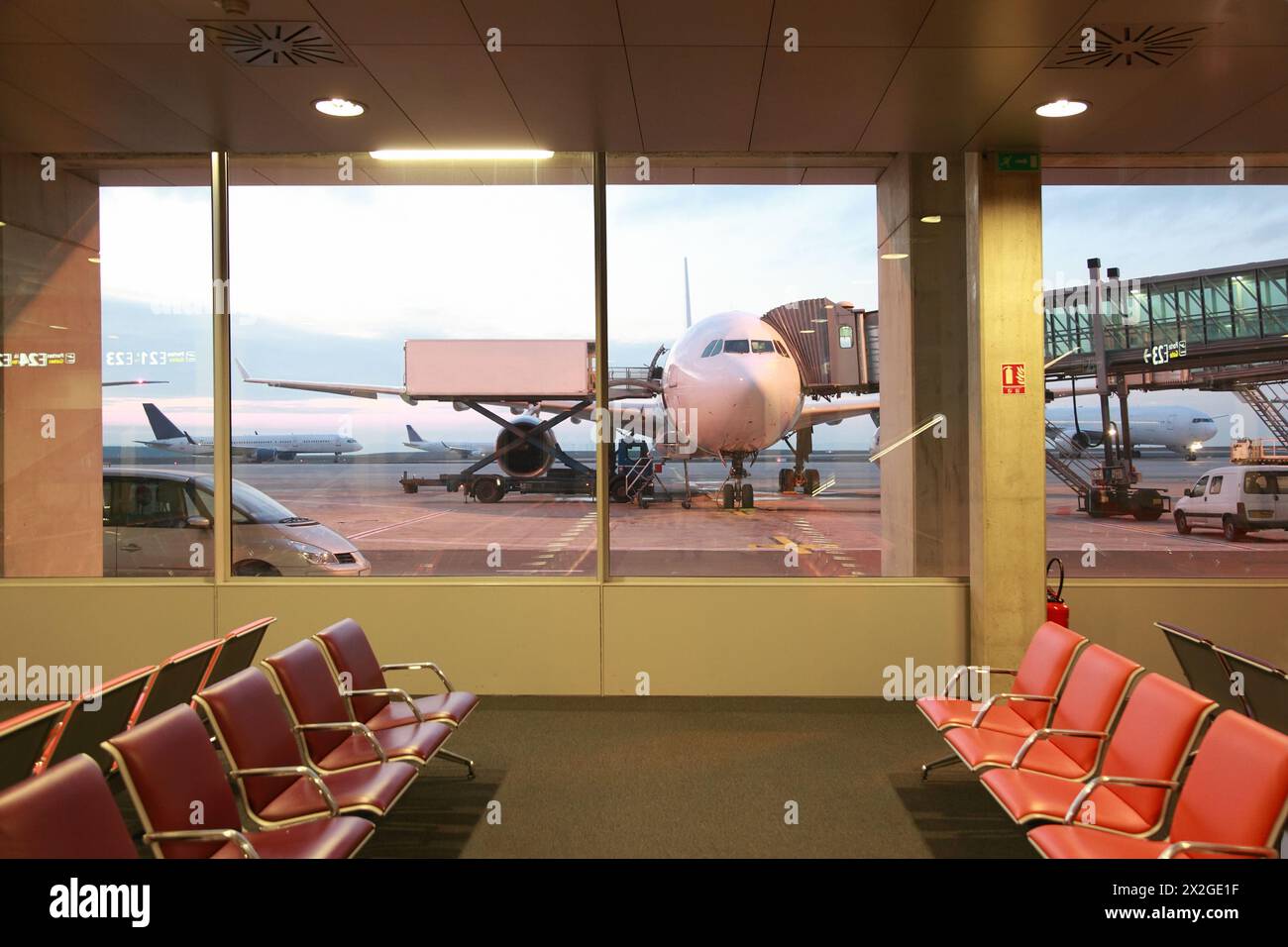 Empty waiting room with red armchairs at Airport, windows, airplanes Stock Photo