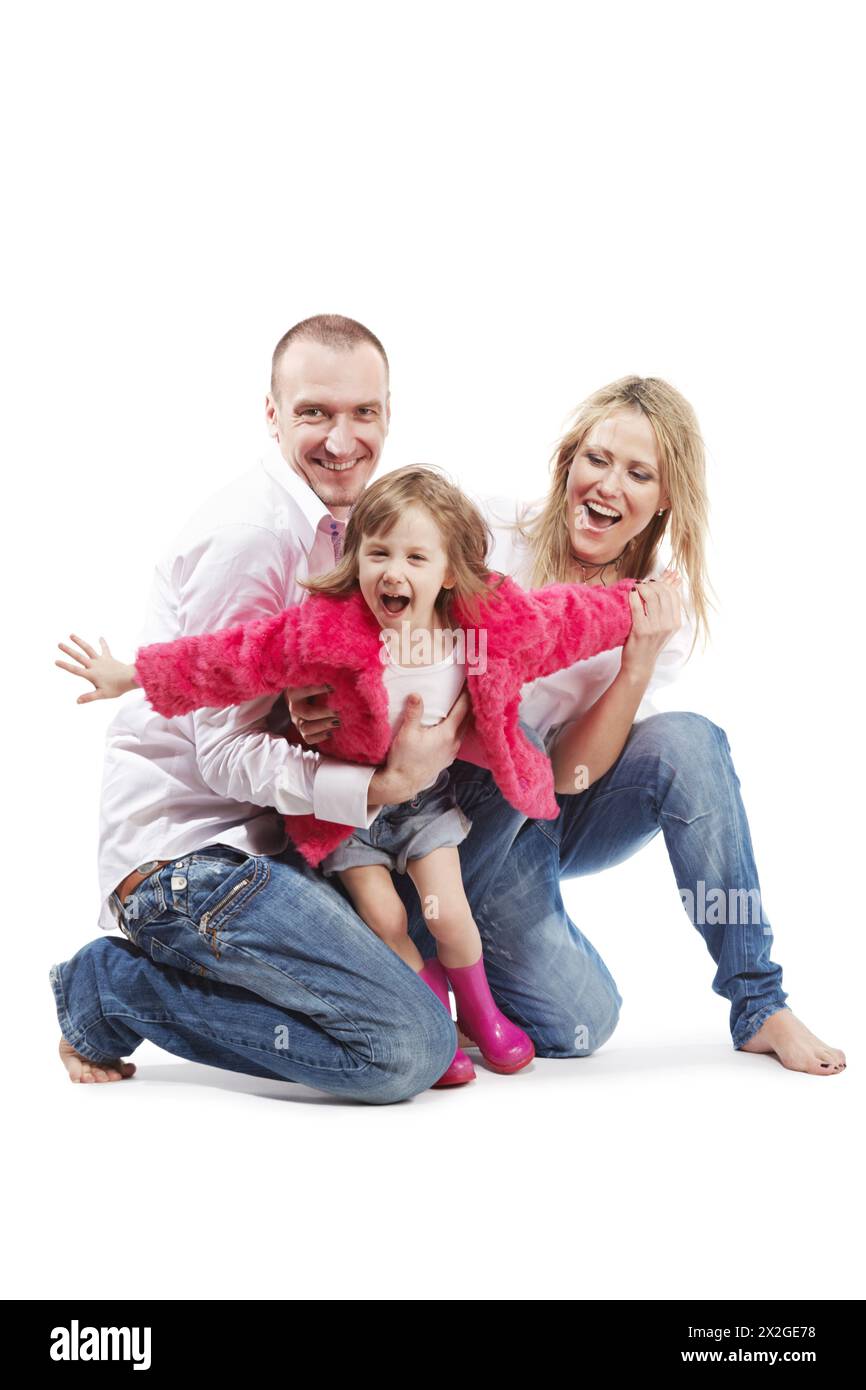 Father and mother in the white shirts and blue jeans bearfooted and little daughter in the pink gumboots and fur jacket with outstretched arms as if s Stock Photo