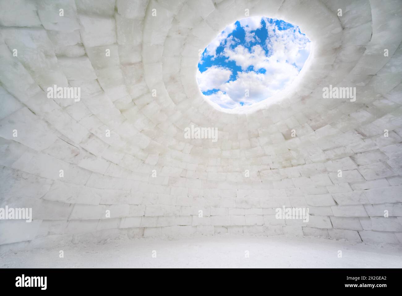 Inside empty house of ice, eskimo igloo, blue sky and clouds Stock Photo