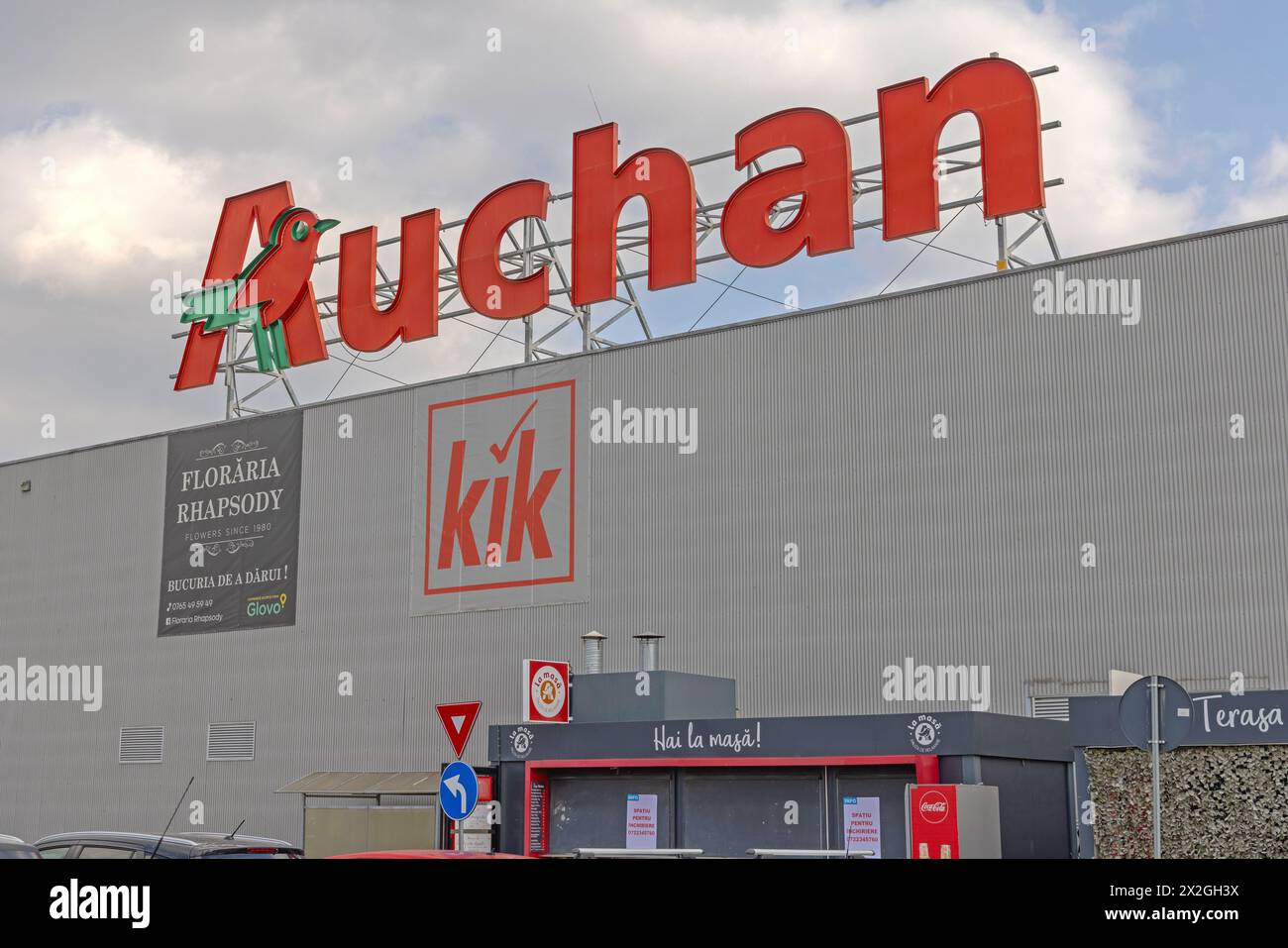 Craiova, Romania - March 16, 2024: Orange 3d Sign Auchan Grocery Store at Top of Hypermarket Building at Severinului Way. Stock Photo