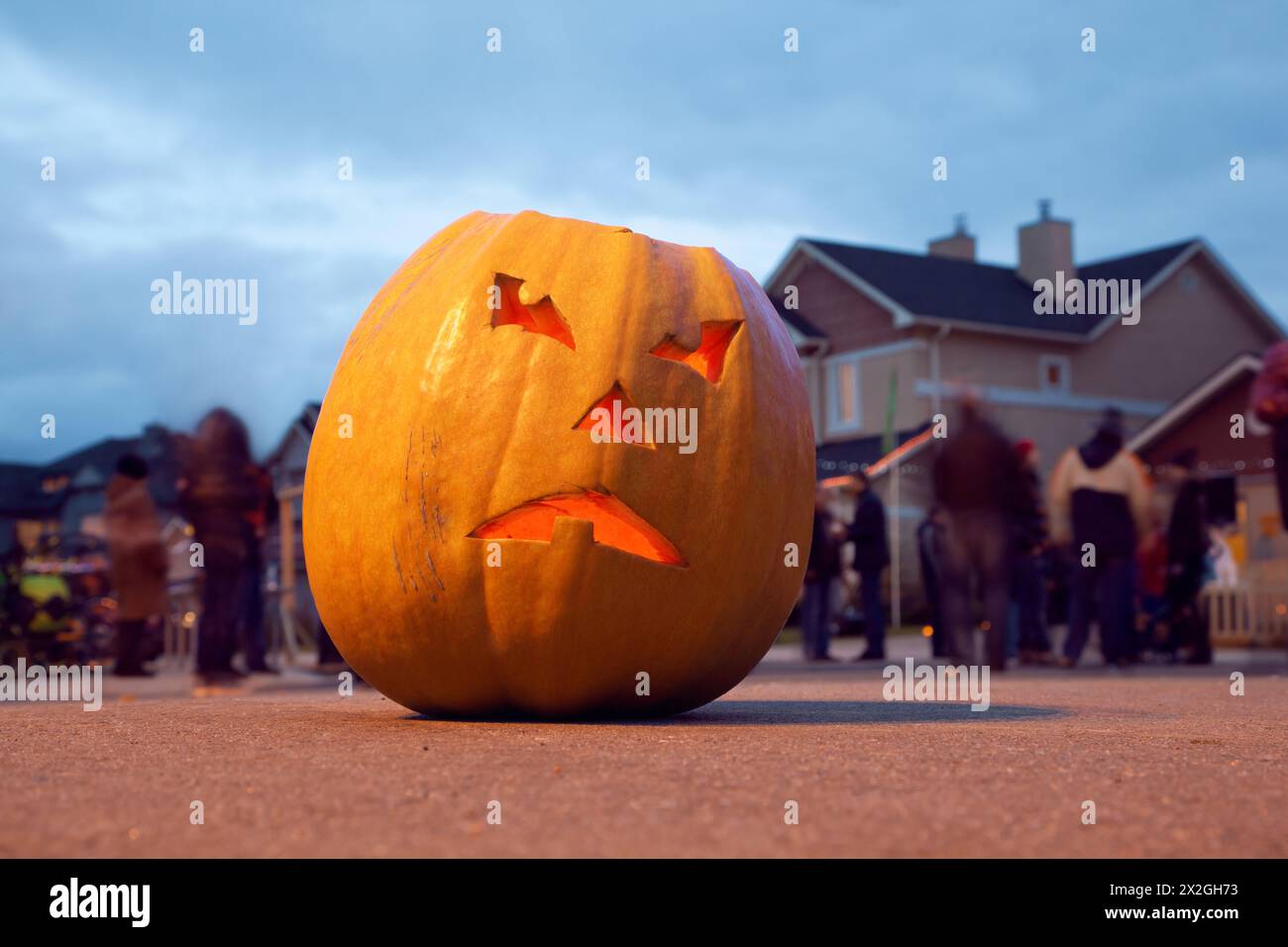 Scary Jack O'Lantern. Halloween pumpkin. Halloween celebrating. Behind pumpkin crowd of people Stock Photo