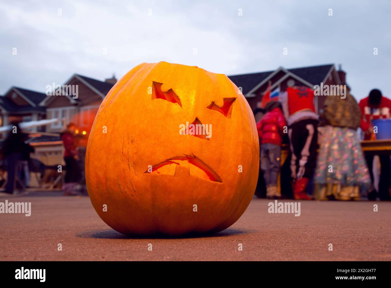 Scary Jack O'Lantern. Halloween pumpkin. Halloween celebrating. Behind pumpkin crowd of people Stock Photo