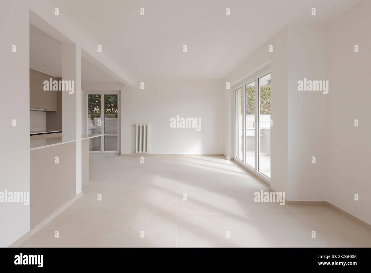 Empty white room with large window, it is a newly renovated and now new flat. A beam of light enters the room, making it very bright. No people inside Stock Photo
