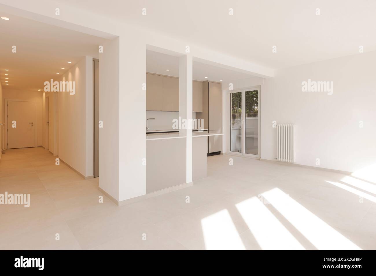 Empty white room with large window, it is a newly renovated and now new flat. A beam of light enters the room, making it very bright. No people inside Stock Photo