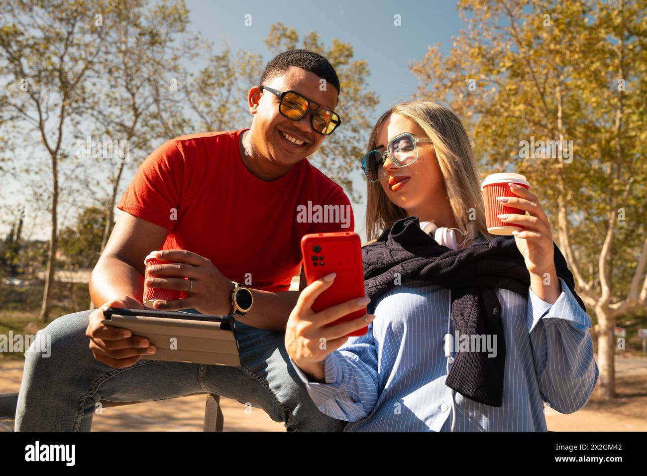 Happy interracial couple checking cell phone outdoors. Stock Photo