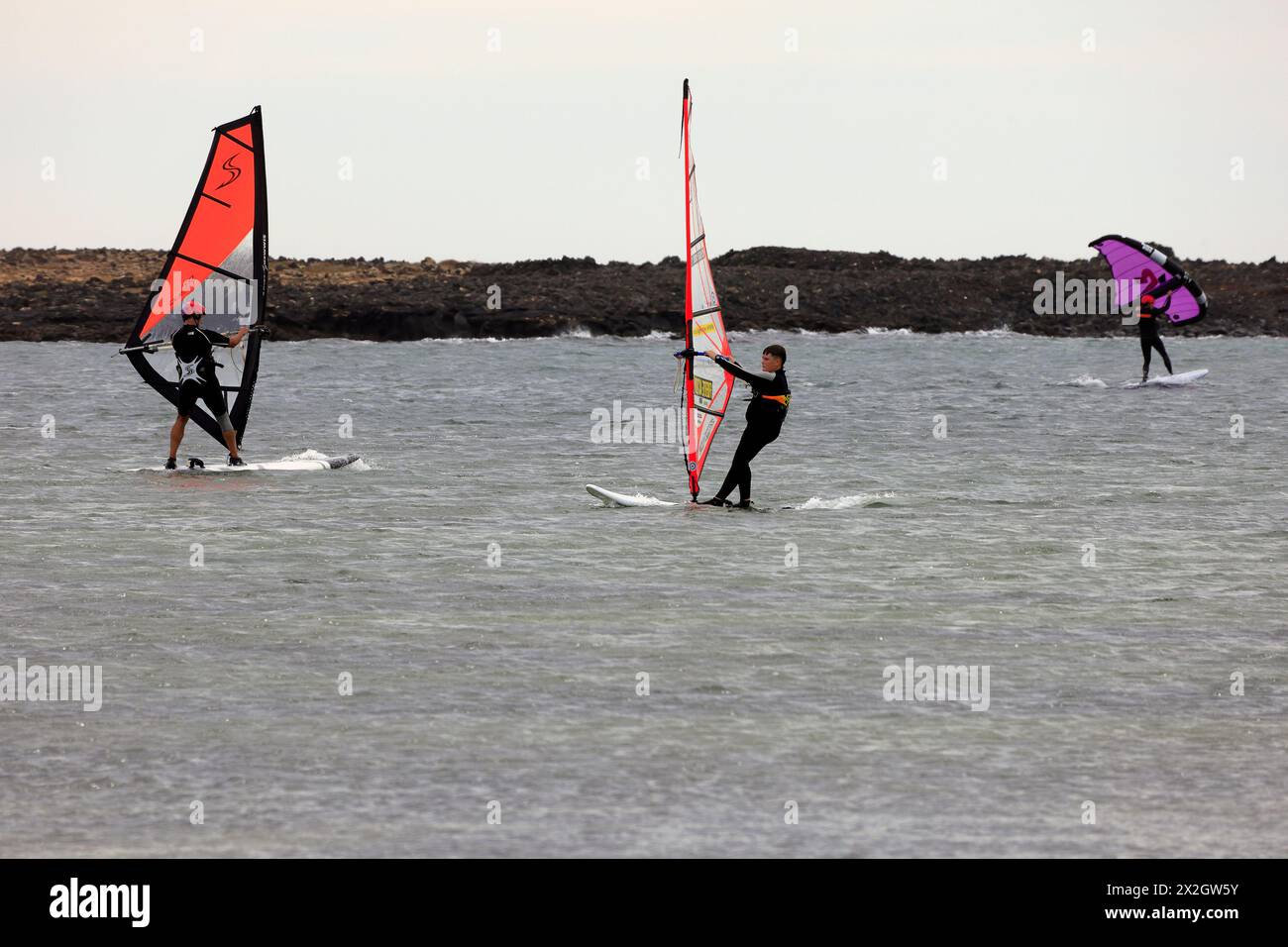 Three wind surfers at El Cotillo, Fuerteventura. Taken February 2024 Stock Photo