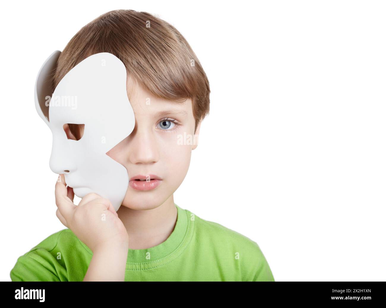 Little boy in the green t-shirt hides half of the face behind the theatrical mask Stock Photo