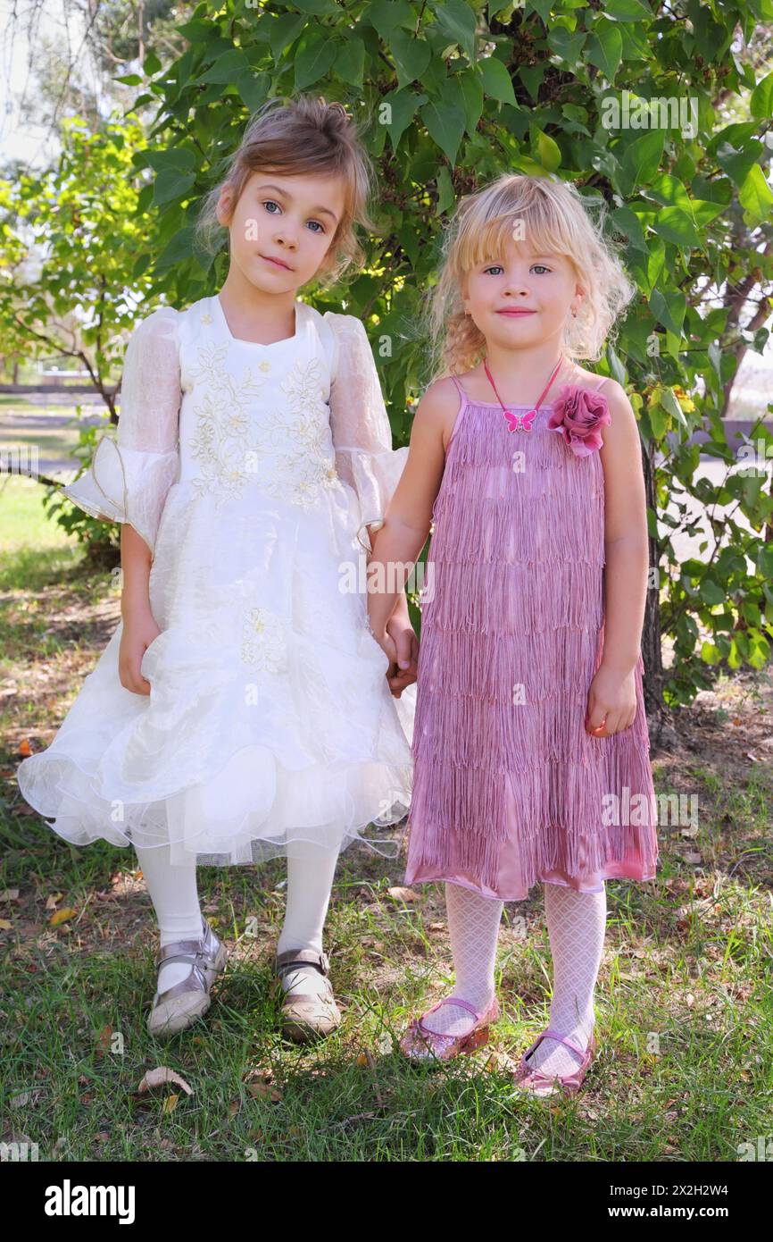 two little girls wearing beautiful dresses holding hands and standing ...