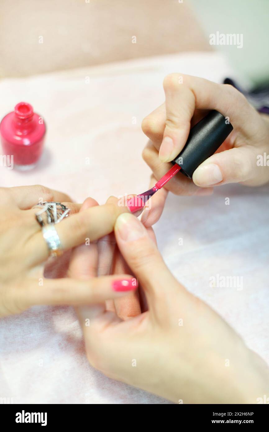 Female hands manicure woman by pink nail polish in beauty salon Stock Photo