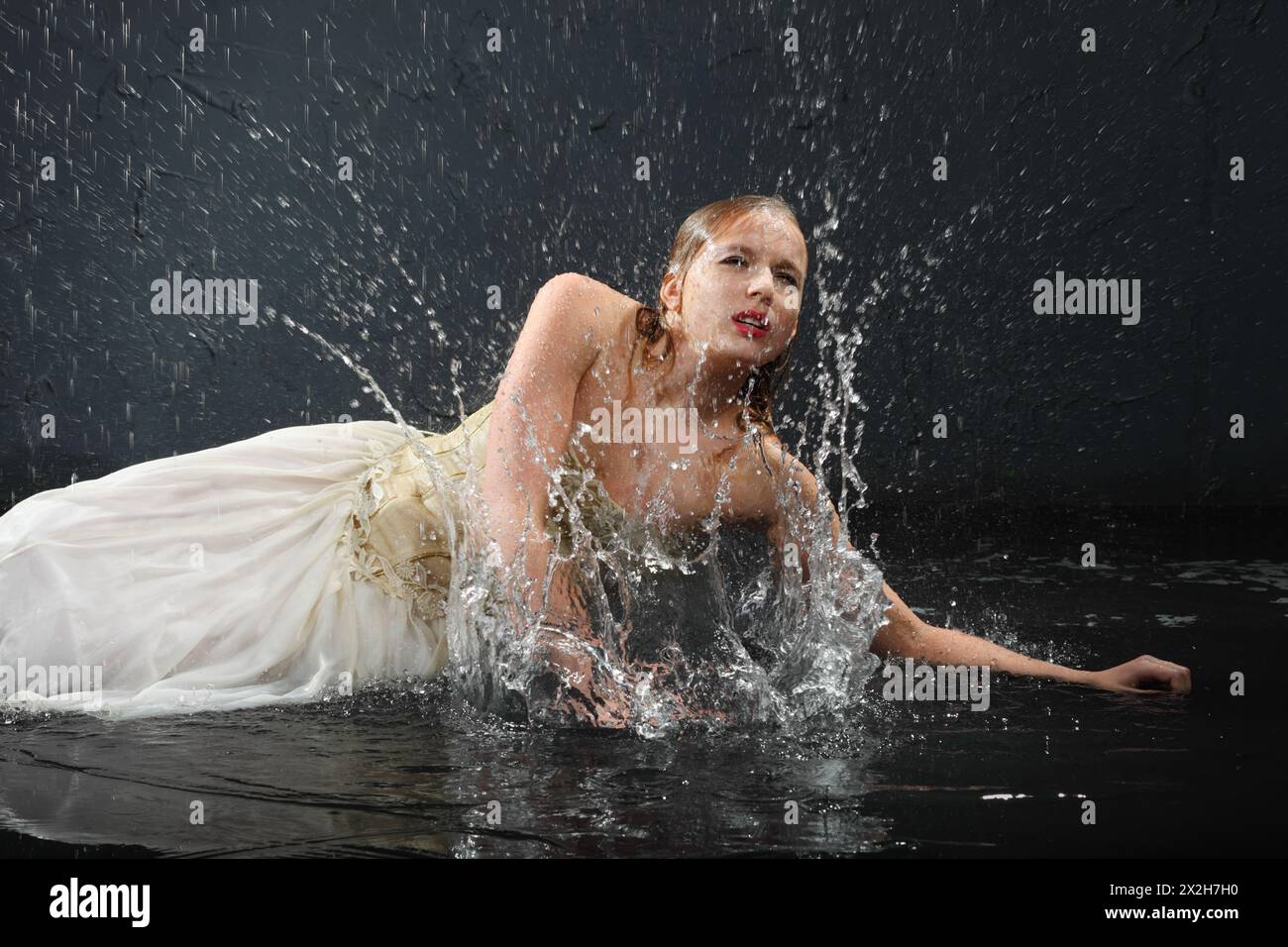 beautiful girl wearing in dress with corset lies on floor and sprays water Stock Photo