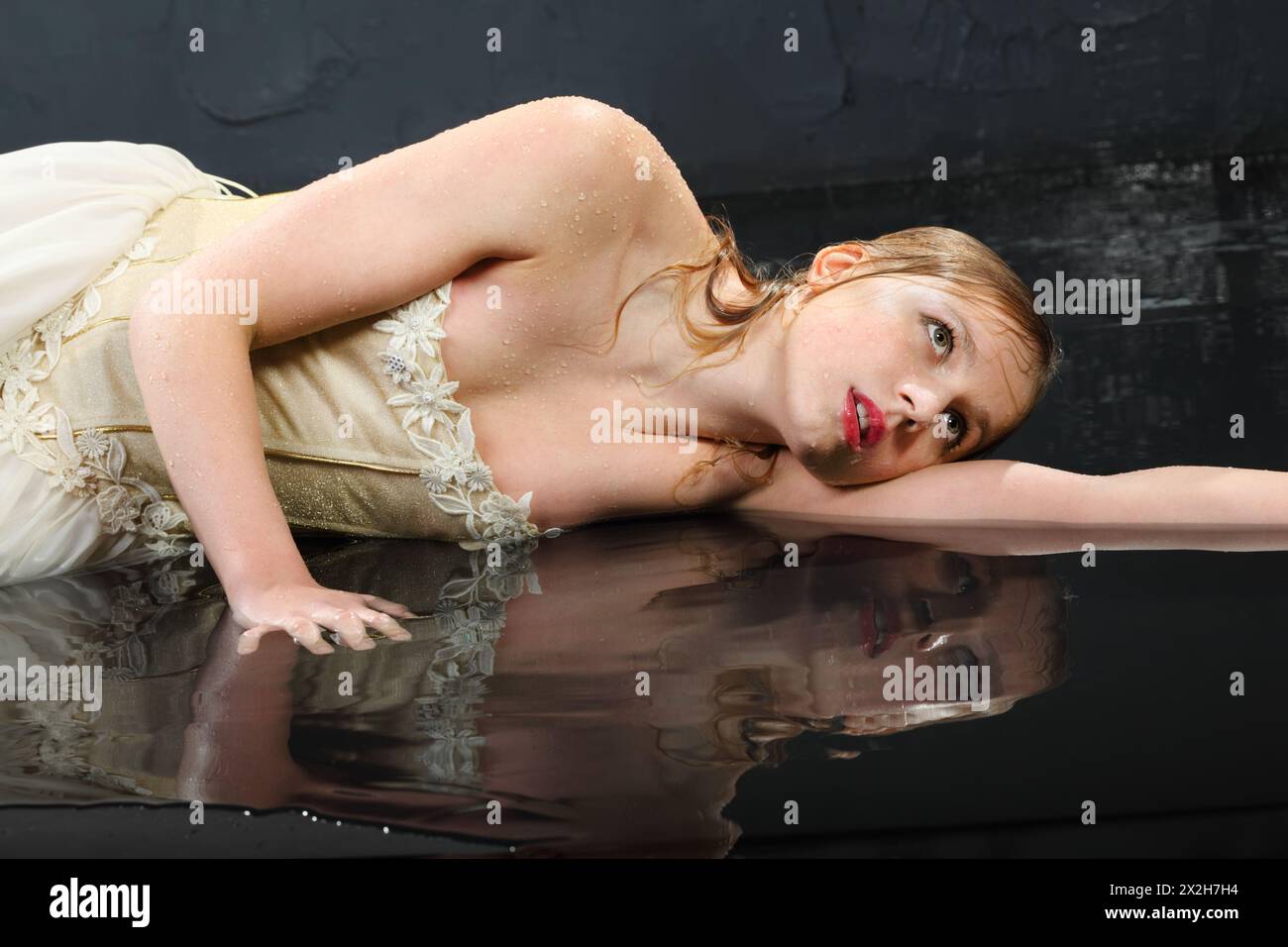 beautifu thoughtfull girl wearing in dress with corset lies on wet floor Stock Photo