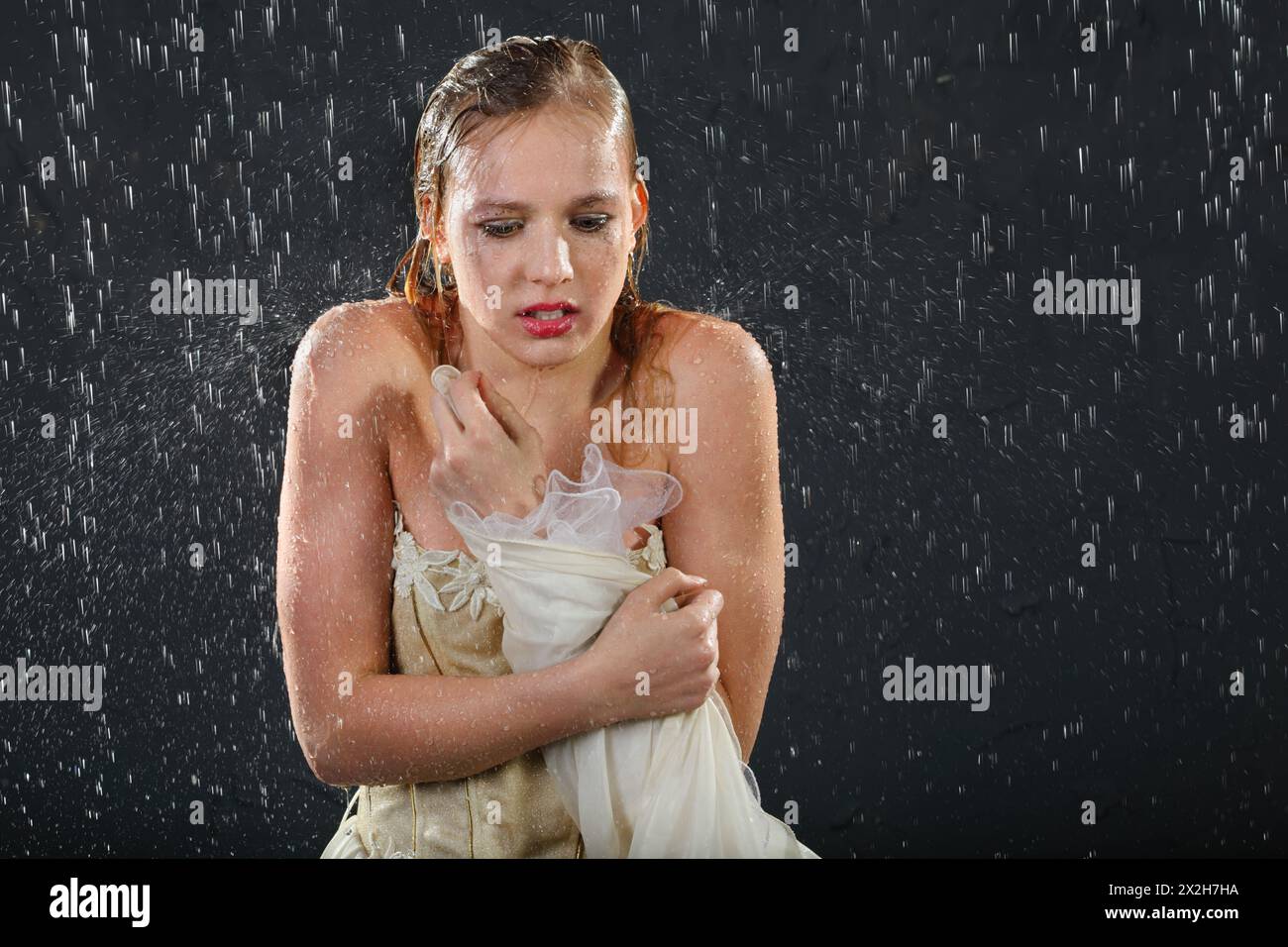 beautiful girl wearing in dress with corset freezes in rain and tries to keep warm Stock Photo