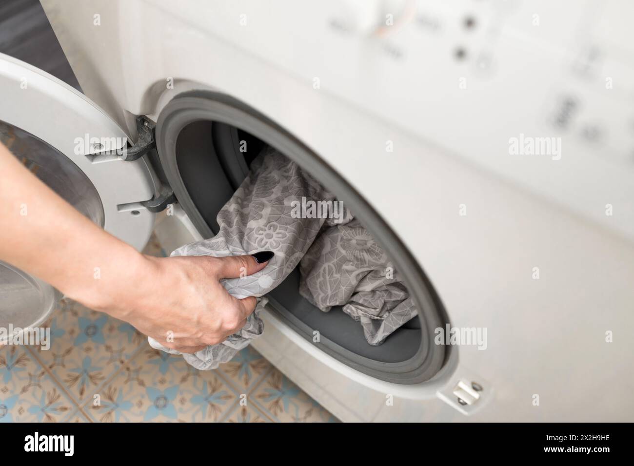 housewife takes out washed clothes from the drum of the washing machine. washing bed linen in a washing machine Stock Photo