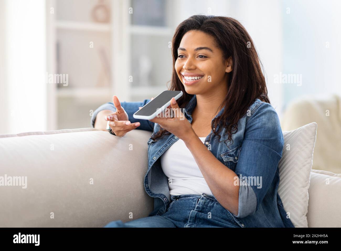 Pretty Black Woman Sitting on Couch Holding Cell Phone Stock Photo - Alamy