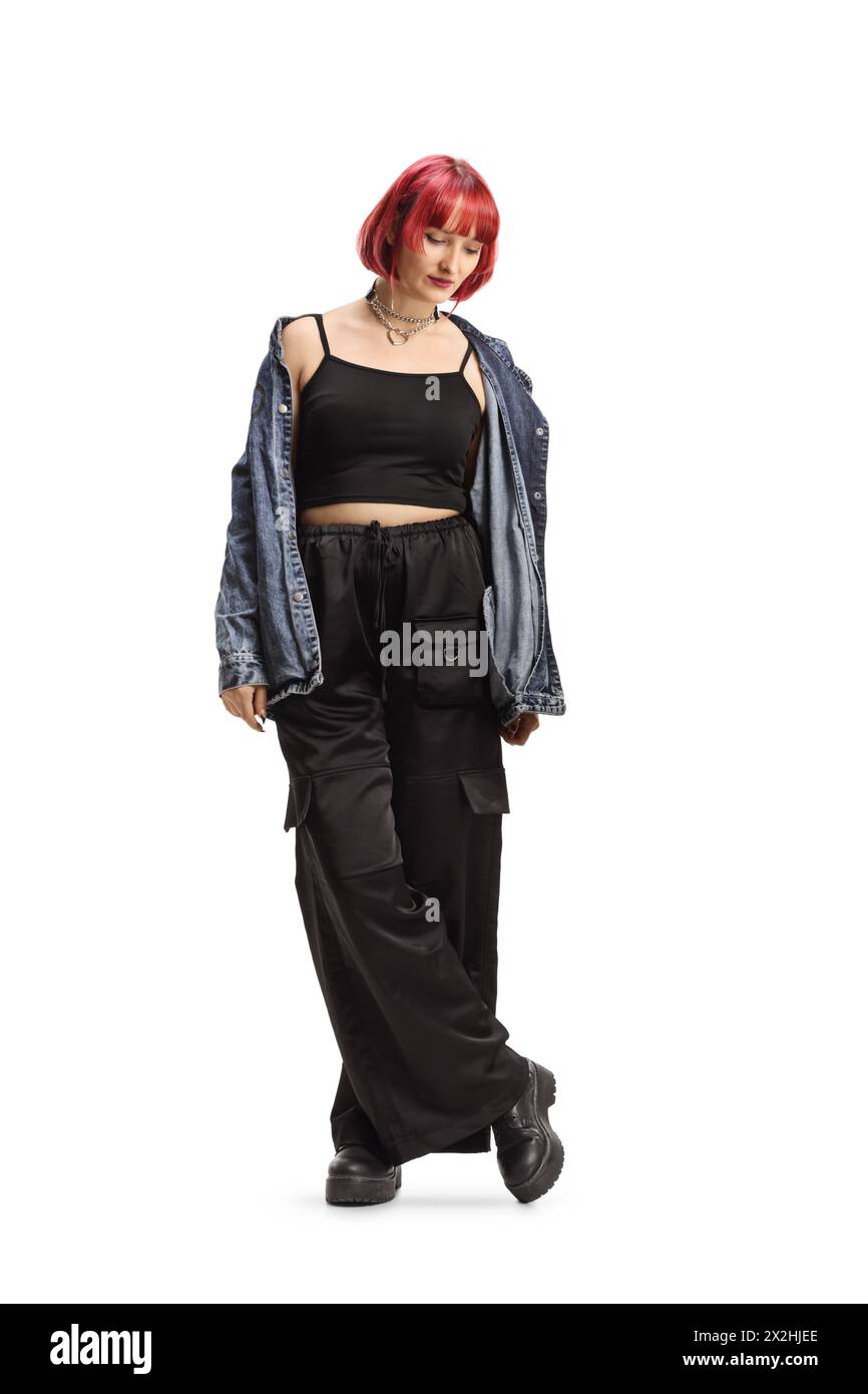 Young female with red heair wearing black wide trousers and denim shirt isolated on white background Stock Photo