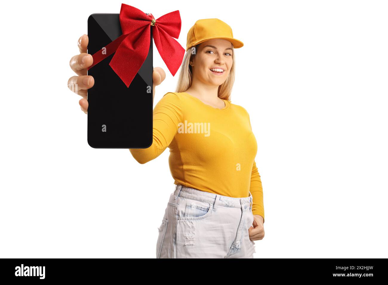 Young female holding a new smartphone with a red bow and pointing isolated on white background Stock Photo