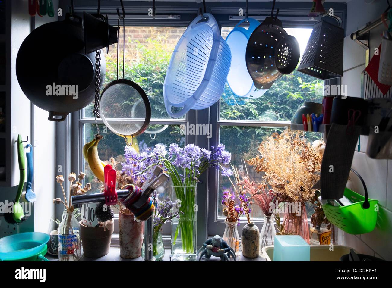 Kitchen utensils hanging above kitchen sink with a view through window home interior inside terraced house in London England UK KATHY DEWITT Stock Photo