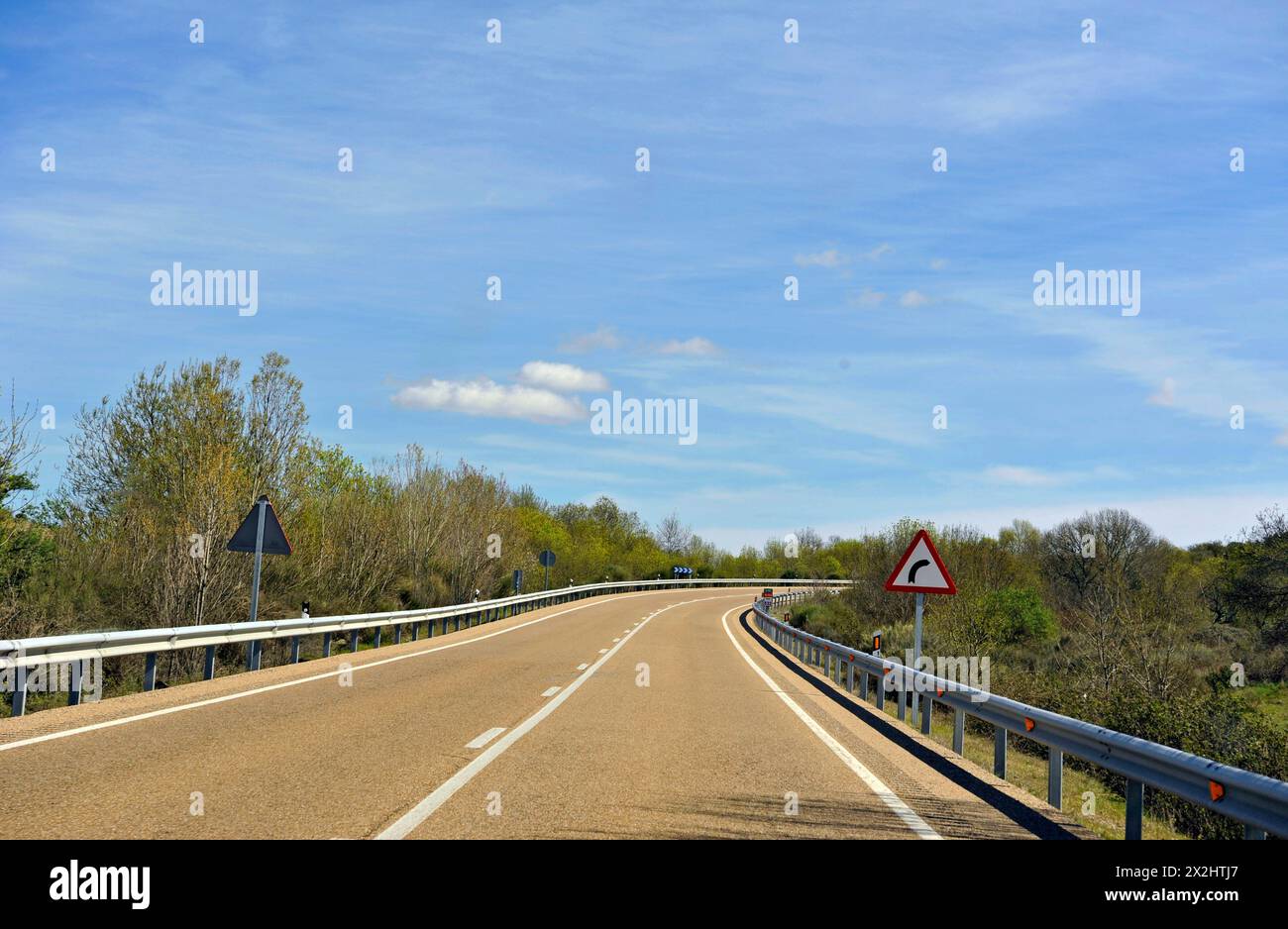 Road with sign indicating curve ahead, Spain, Europe Stock Photo
