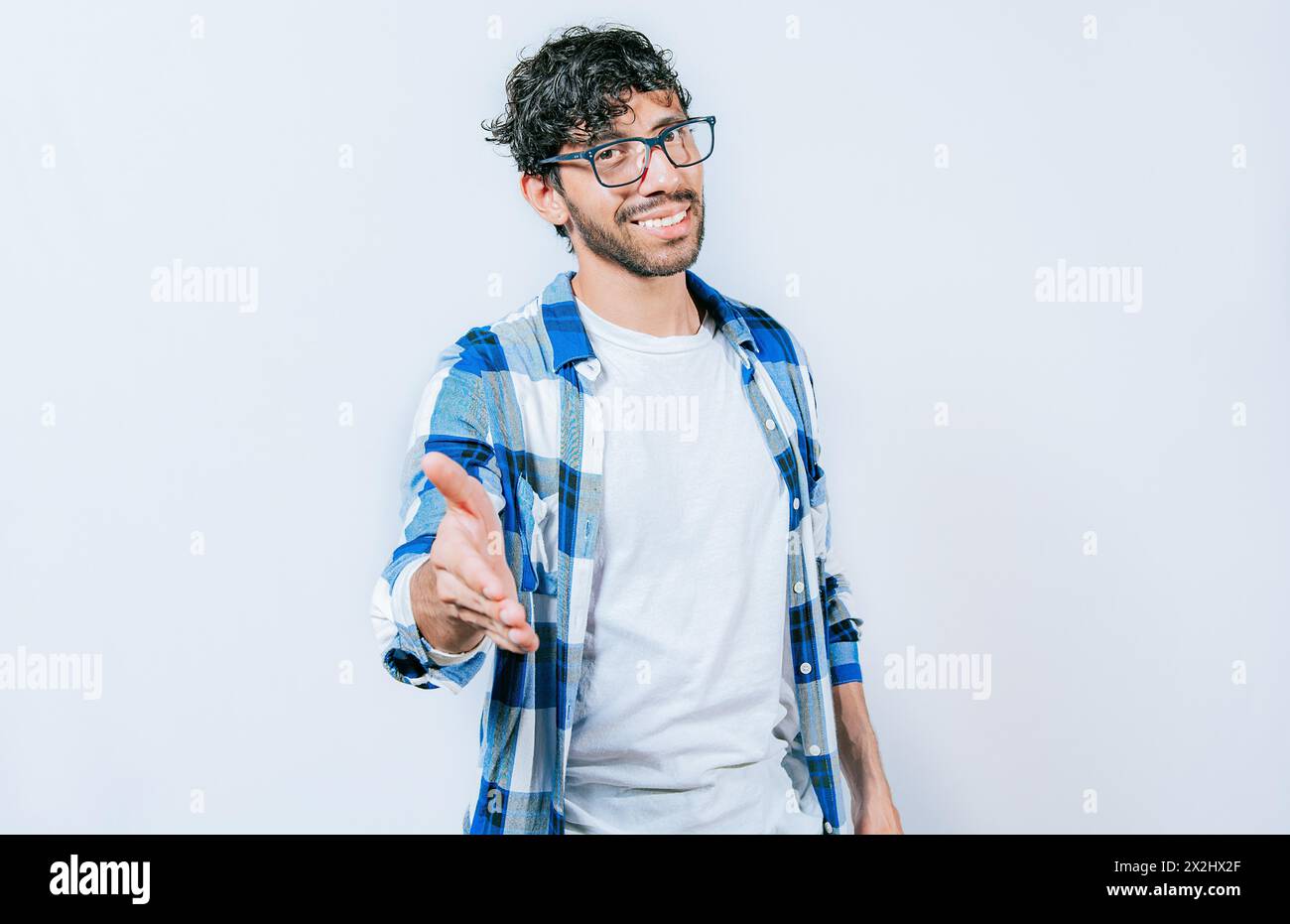 Smiling young man shaking his hand at the camera. Guy in glasses