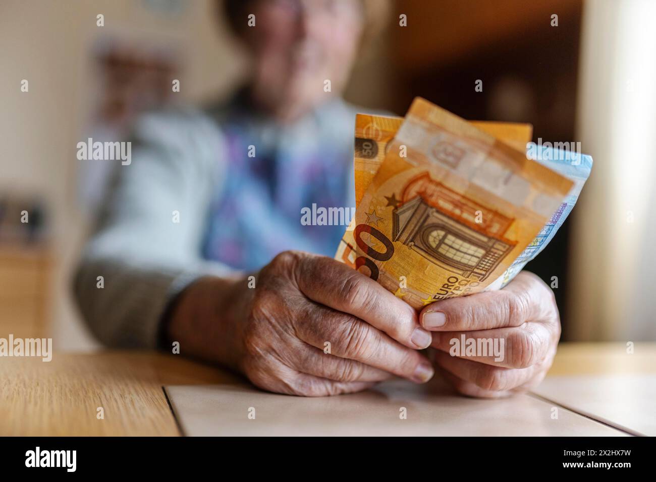 Senior citizen with wrinkled hands counts her money at home in her flat and holds banknotes in her hand, Cologne, North Rhine-Westphalia, Germany Stock Photo