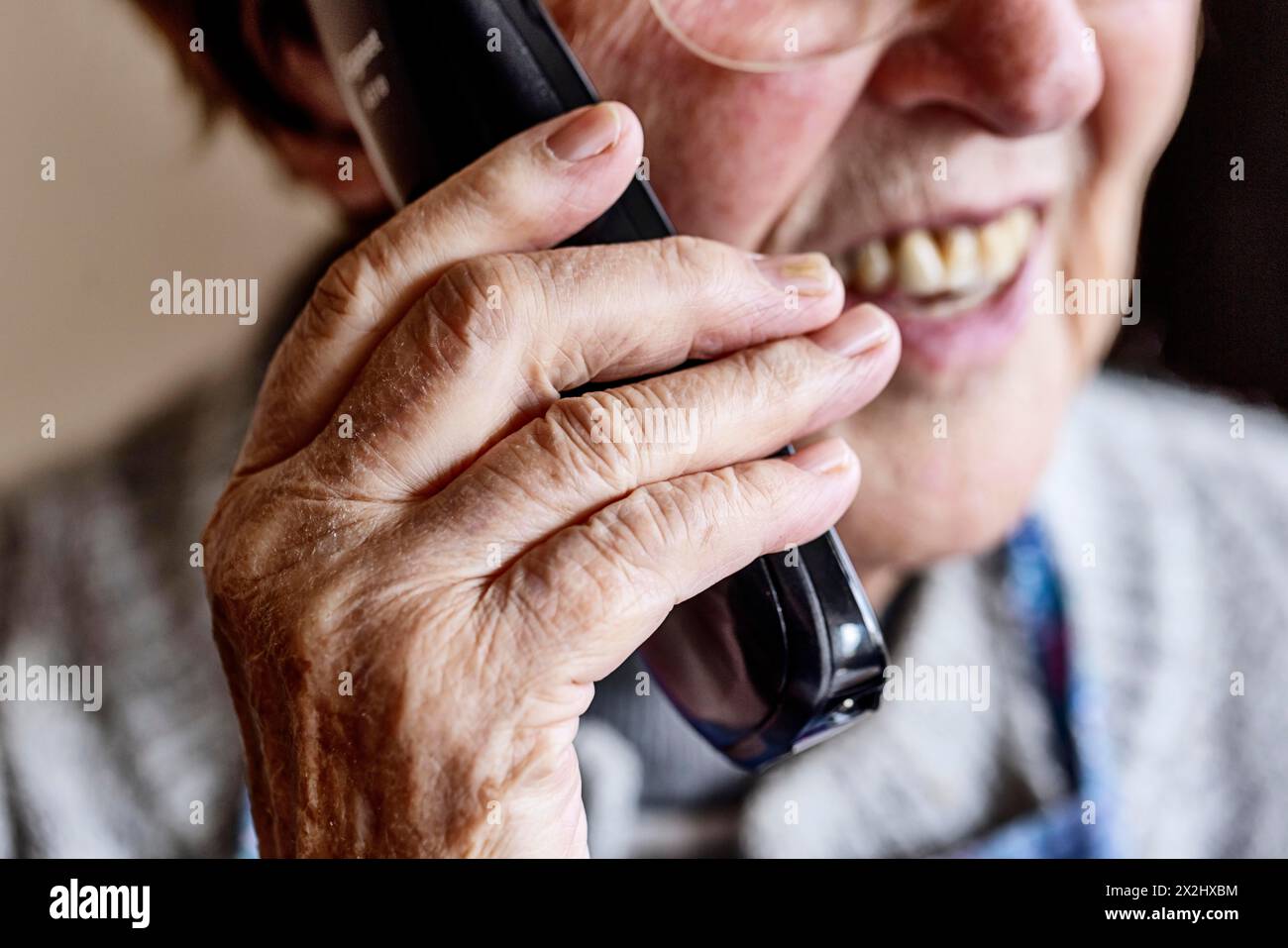 Mouth, hands and telephone receiver of a senior citizen making a phone call, close-up, Cologne, North Rhine-Westphalia, Germany Stock Photo