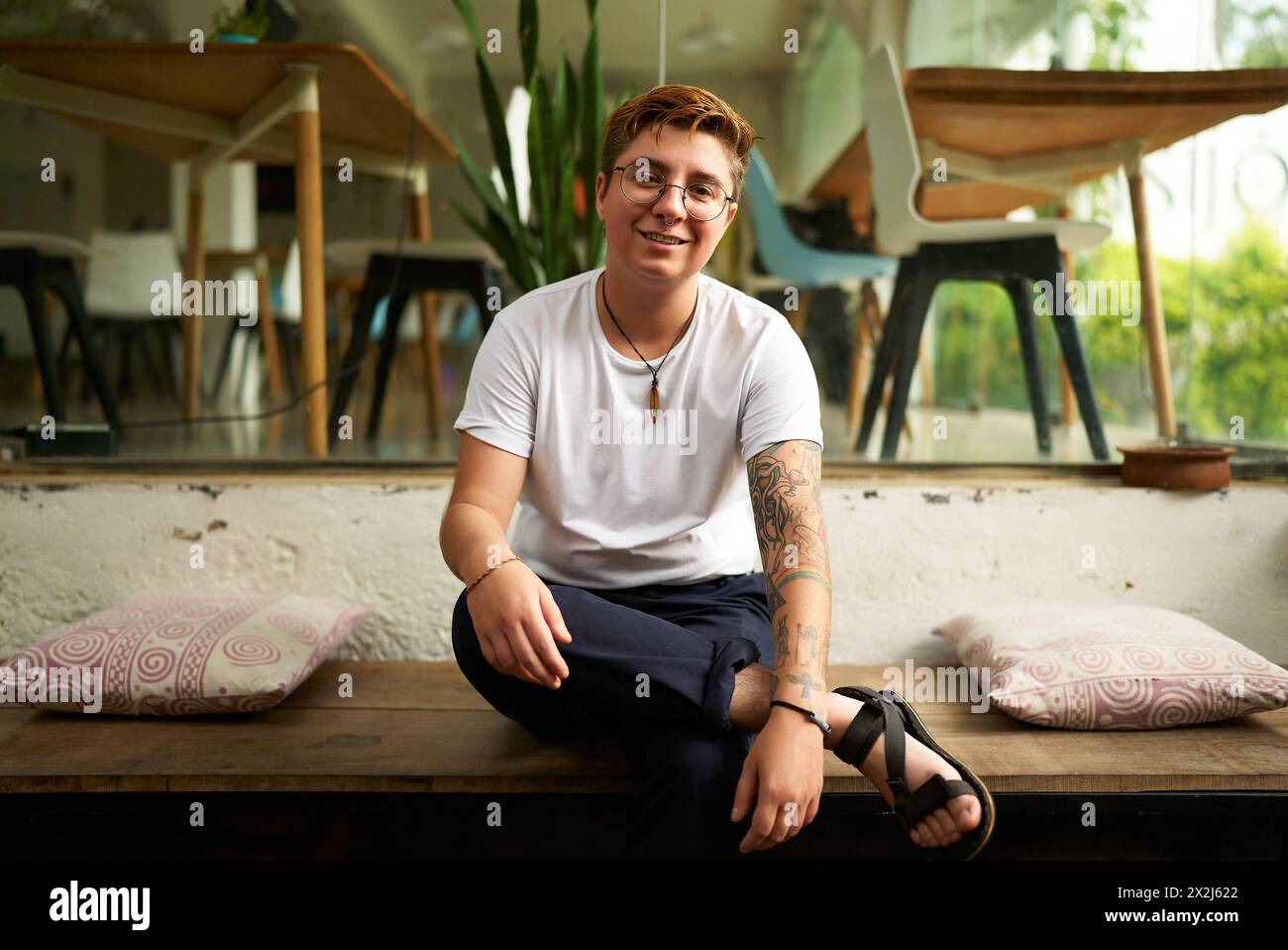 Smiling Gen Z transgender office worker in smart casual clothes sits on