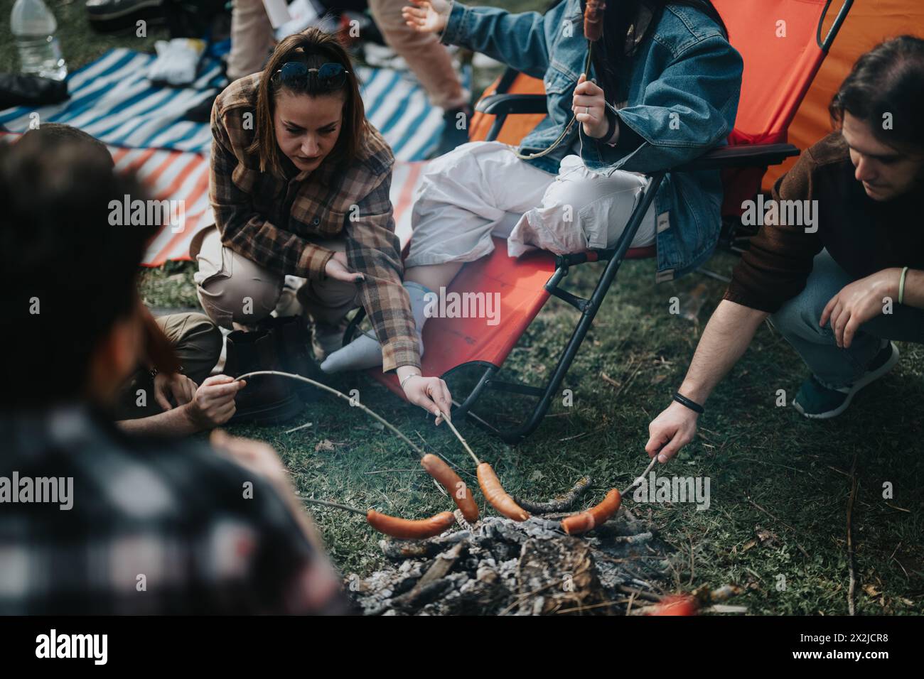 Friends enjoying a camping trip with a casual sausage barbecue Stock Photo