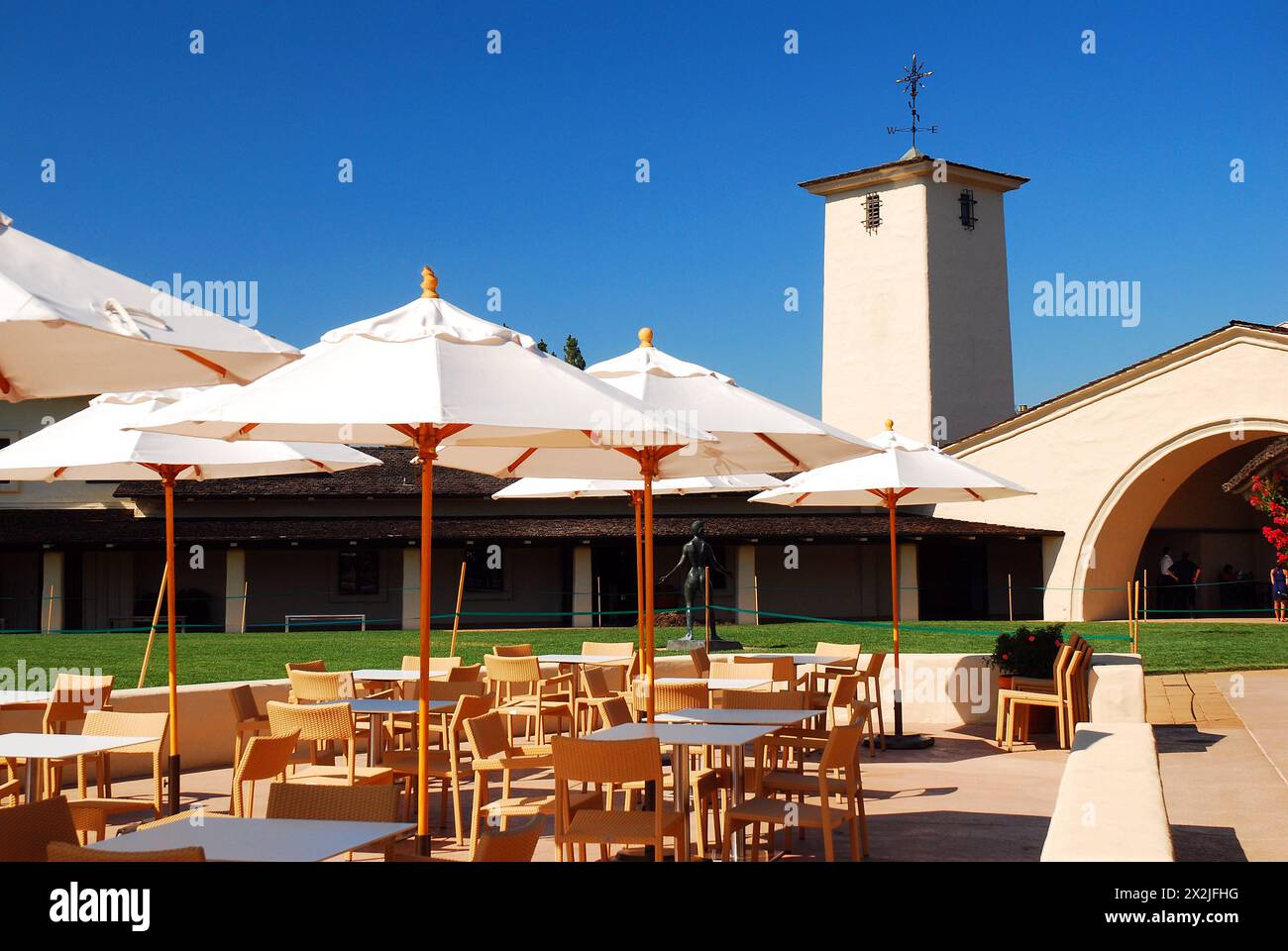 Café tables with shade umbrellas are set up in the back area of the Robert Mondavi Winery in Napa, California Stock Photo