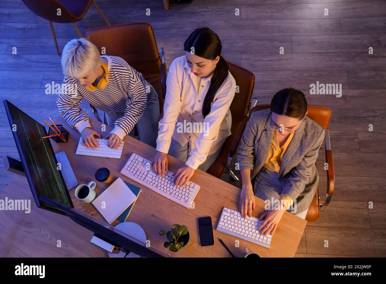 Team of female programmers working in office at night, top view Stock Photo