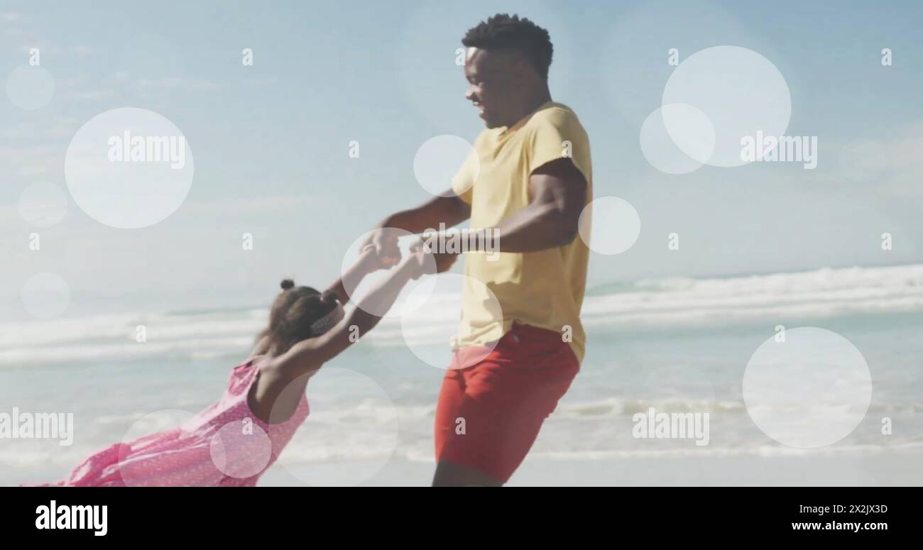 Image of light spots over african american father and daughter playing on beach Stock Photo