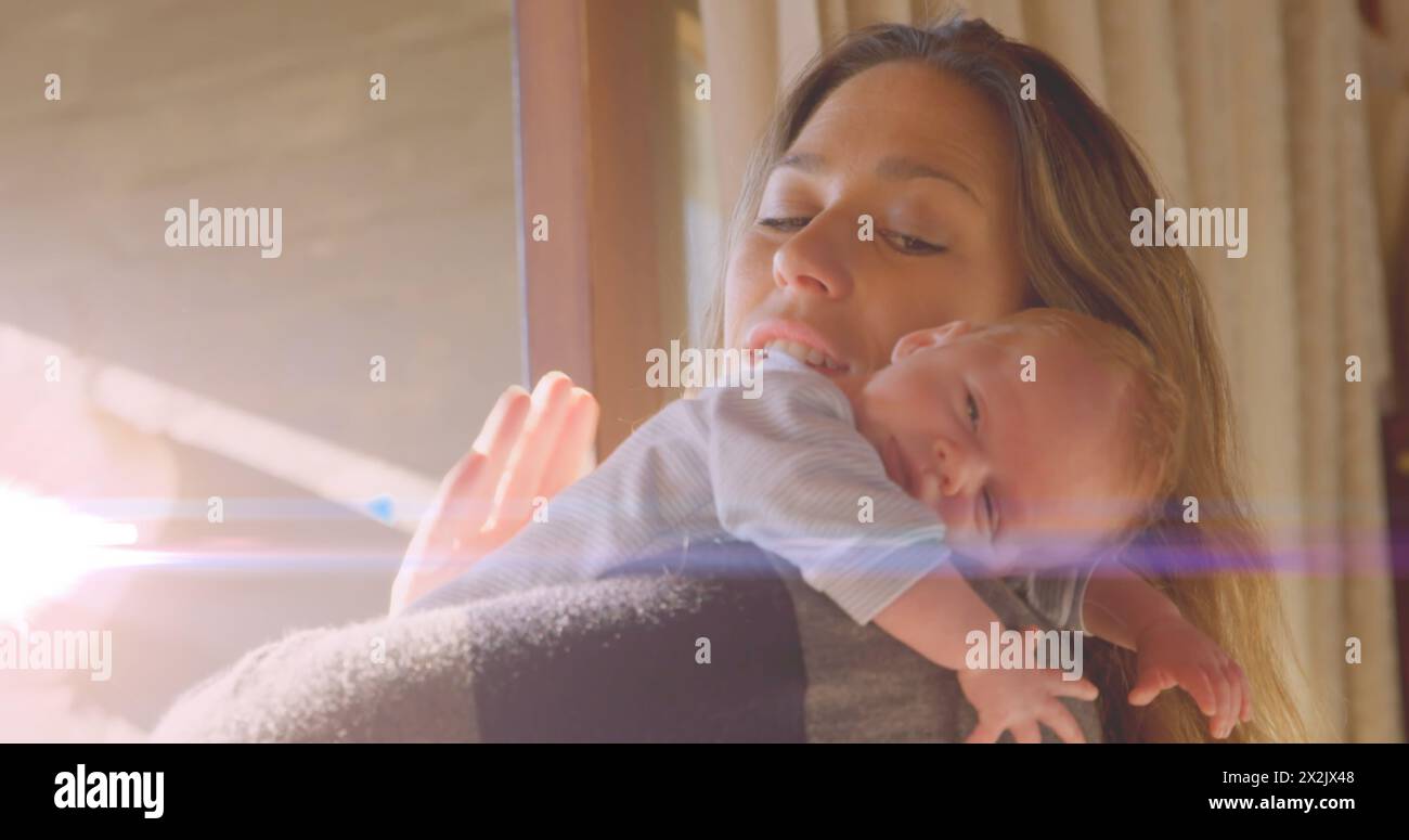 Image of glowing spots over happy caucasian mother with sleeping baby Stock Photo