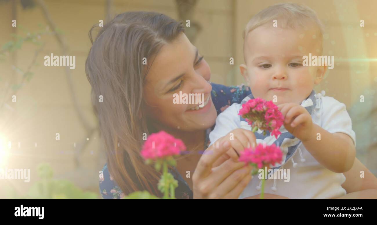 Image of glowing spots over happy caucasian mother with daughter holding flowers Stock Photo