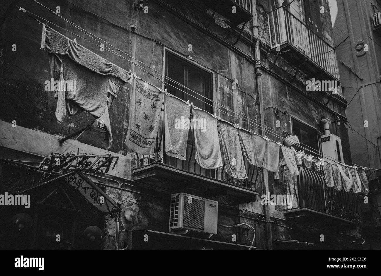 A monochrome photo capturing an old neighborhood with hanging laundry across narrow buildings, bringing a sense of community and daily life in an urba Stock Photo