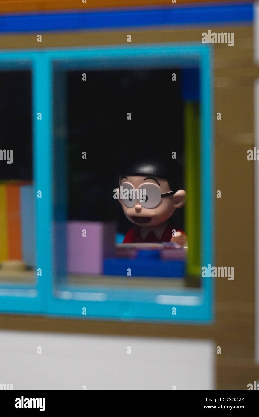Japanese toy figure (Nobita) sitting on the study table and visible from the window Stock Photo