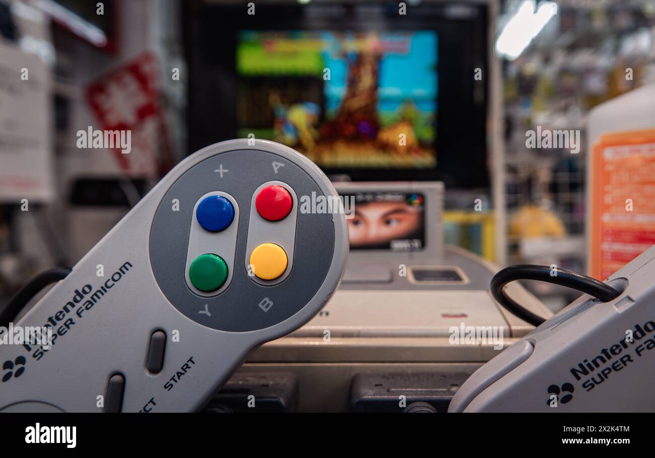 A close-up photo of a Nintendo Super Famicom gamepad in a store setting with blurred gaming background. The image evokes nostalgic feelings related to Stock Photo