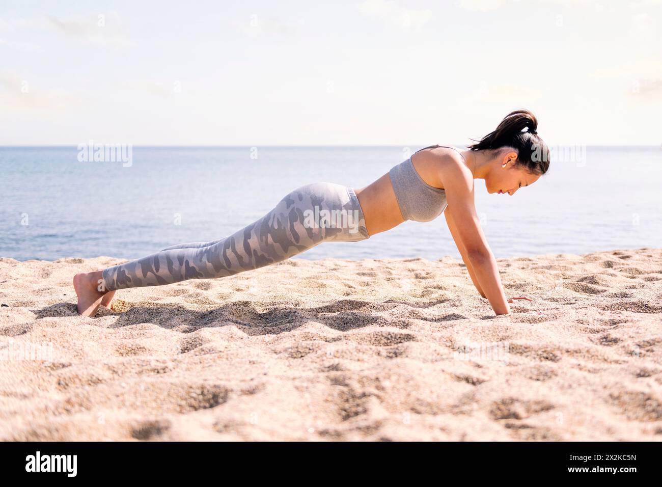 woman in sportswear doing push ups at beach Stock Photo