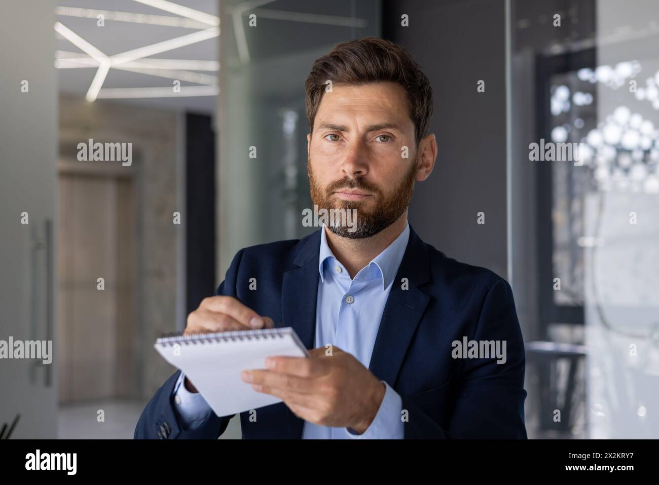 Focused professional businessman in a suit taking notes and looking at ...