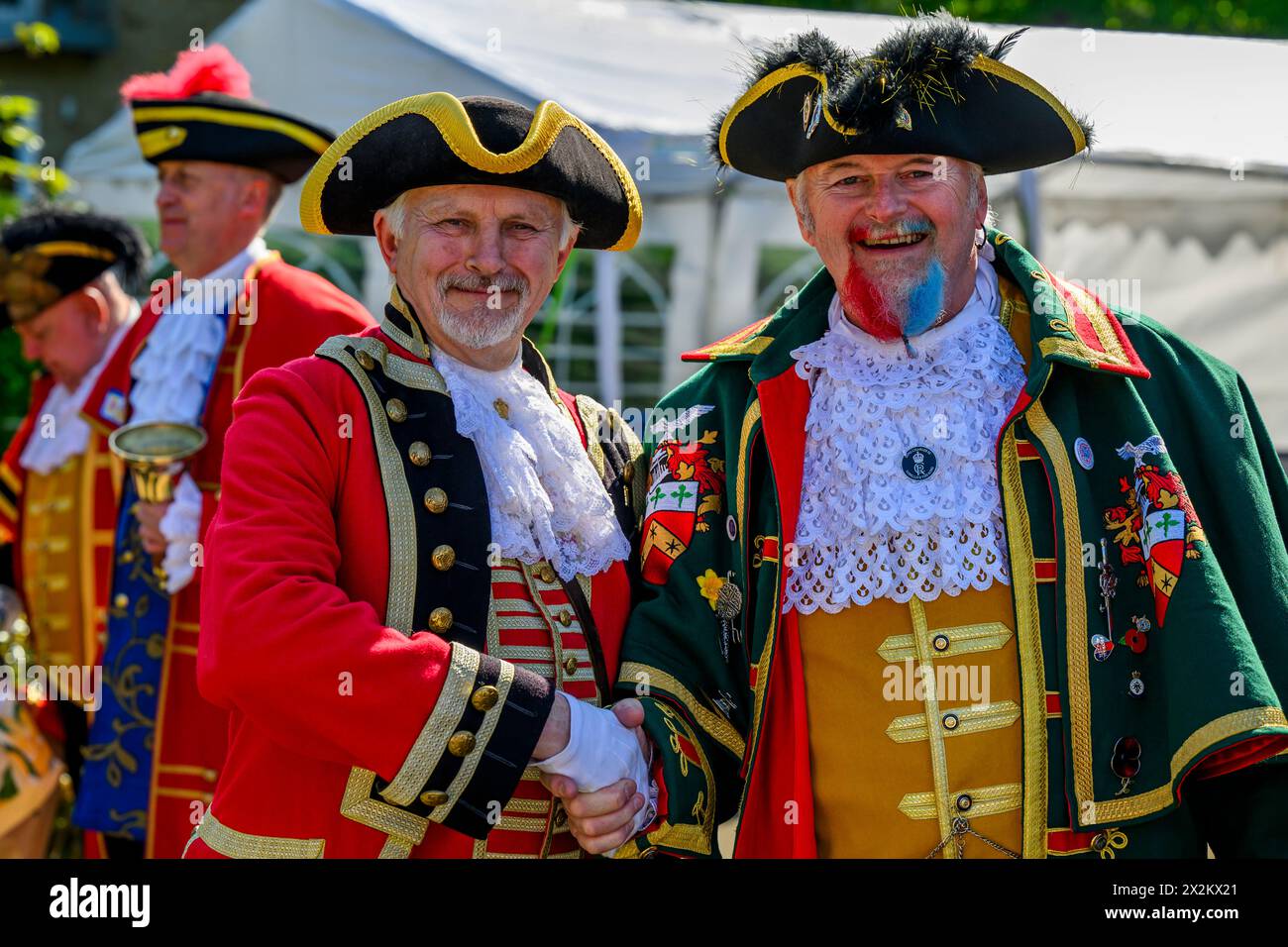 Town criers standing giving friendly handshake (colourful braided crier's livery) smile & pose looking at camera - Ilkley, West Yorkshire, England UK. Stock Photo