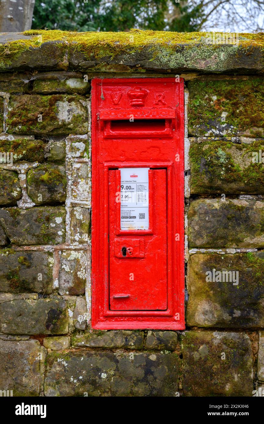 A Victorian red postbox inset in a stone wall in the historic market town of Horsham, West Sussex, England. Stock Photo