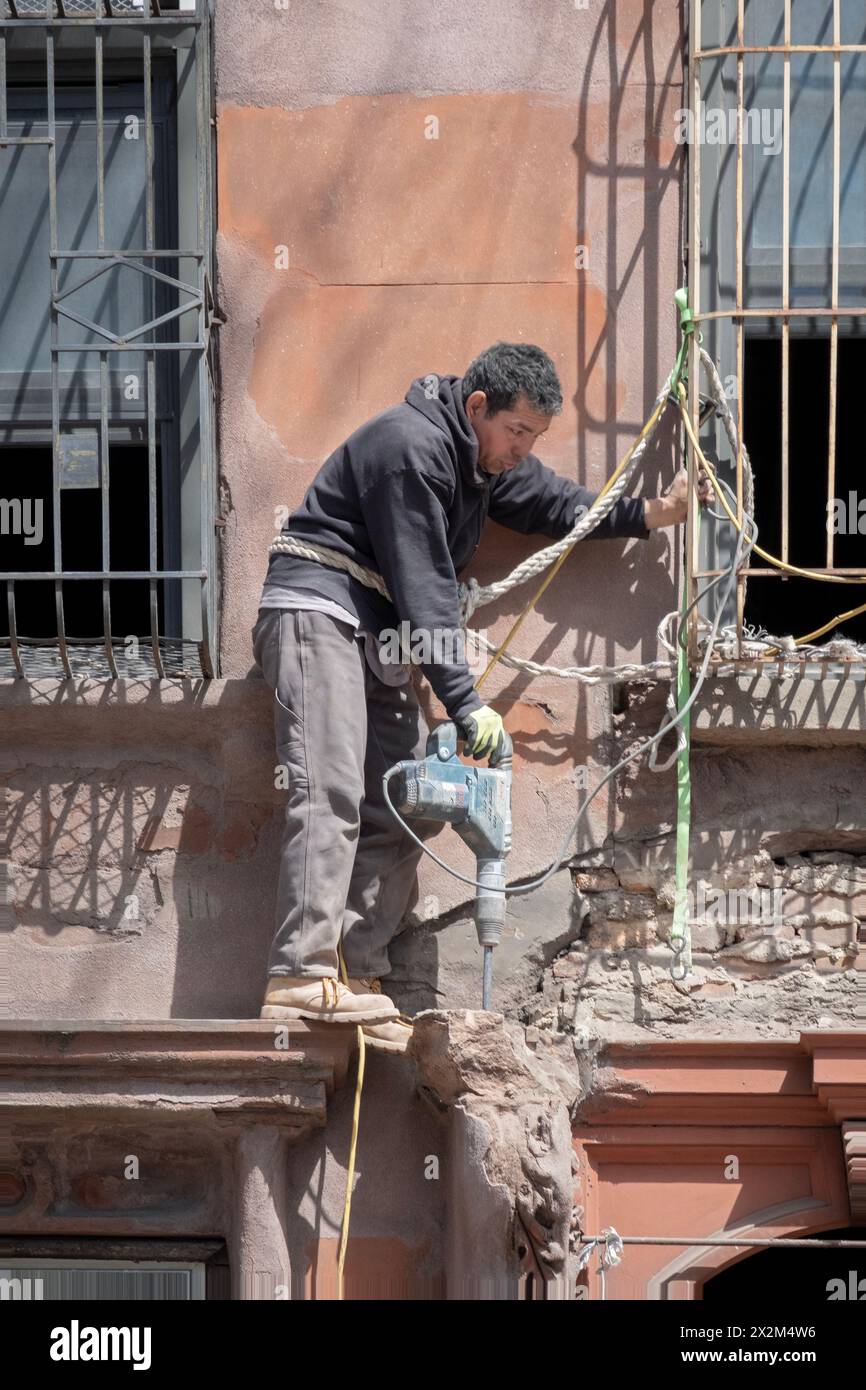 A Construction Worker In A Precarious Position Breaks Concrete With His A Construction Worker In A Precarious Position Breaks Concrete With His