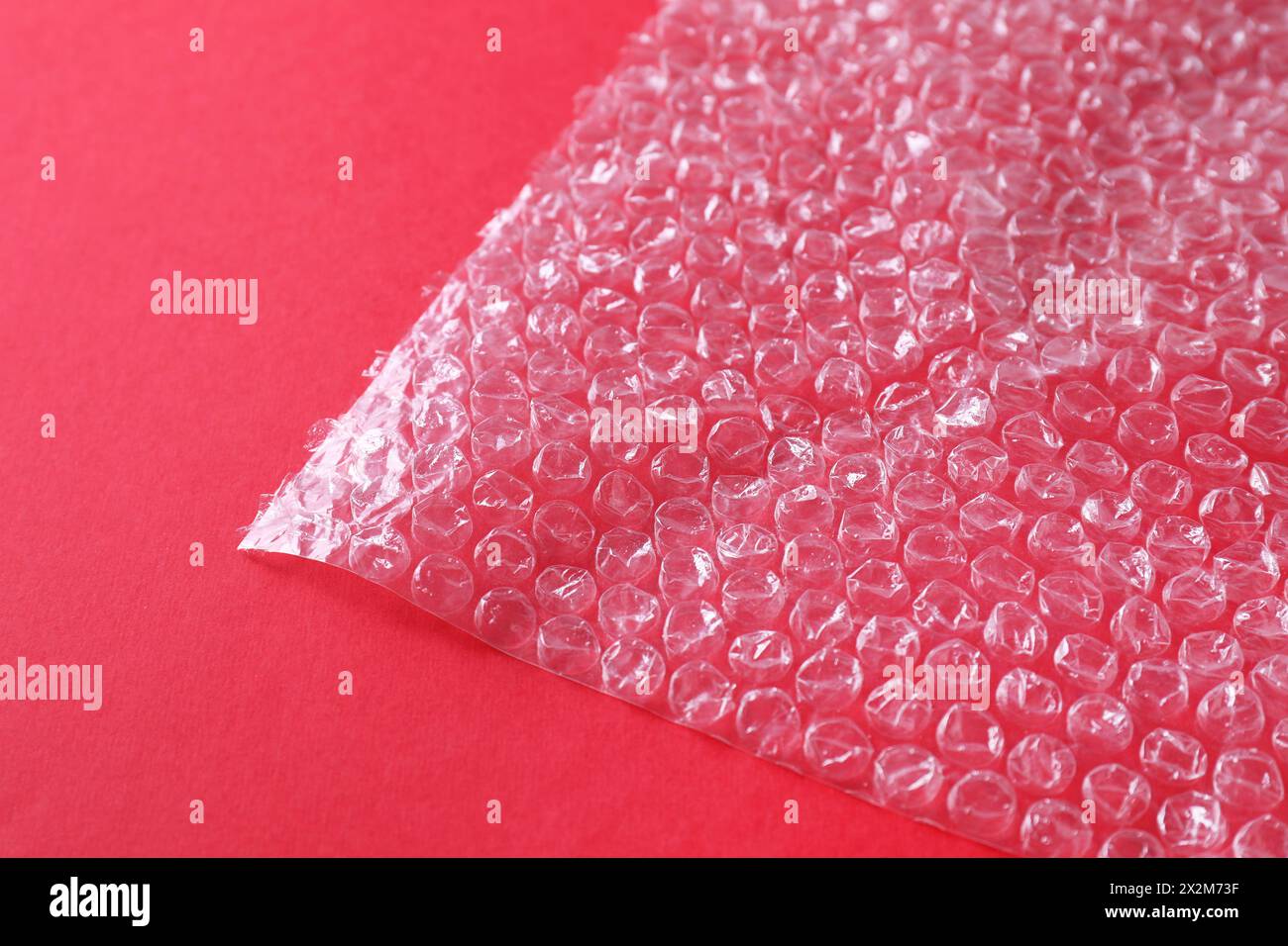 Transparent bubble wrap on red background, closeup Stock Photo