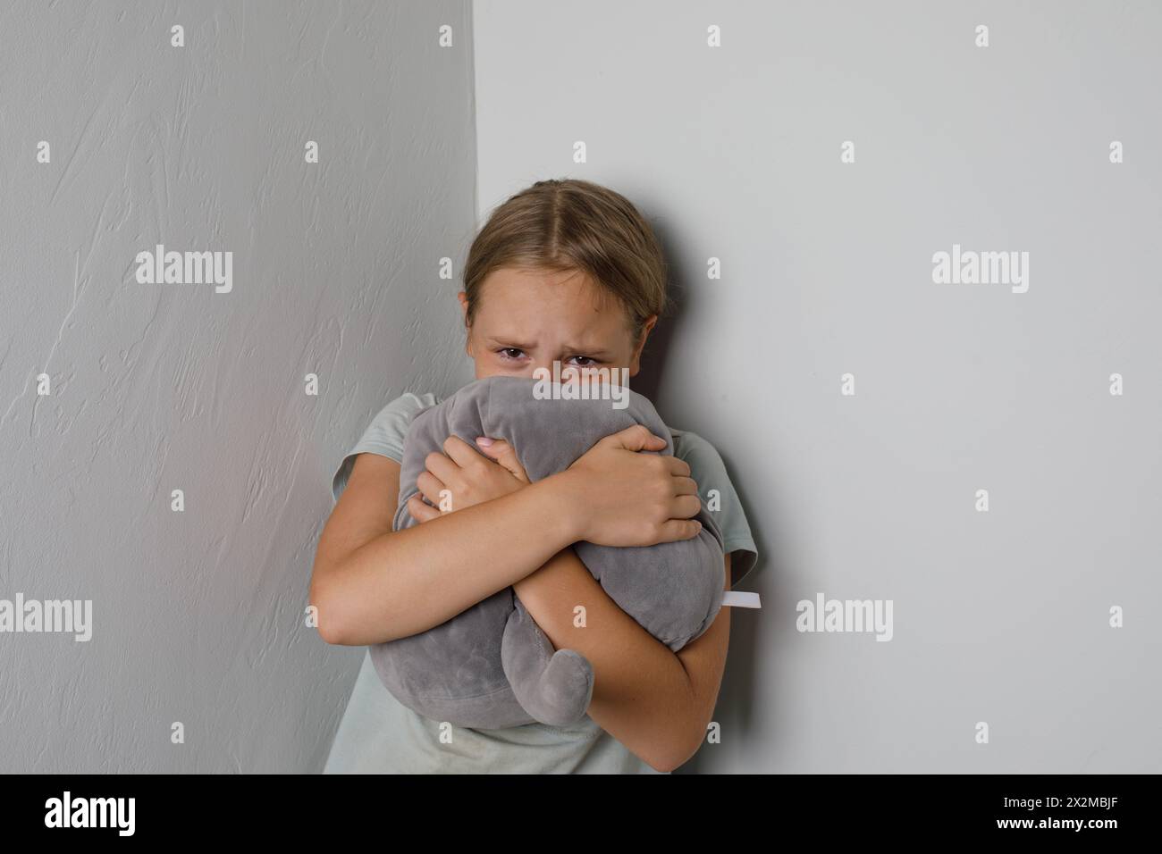Sad young girl crying and looking at camera at home Stock Photo