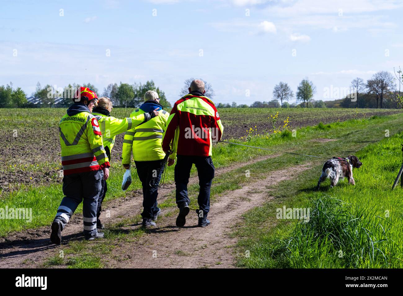 Lower Saxony, Germany. 23 April 2024, Lower Saxony, Bremervörde: Emergency services with a sniffer dog run along a dirt track. More than three hundred emergency services have been searching for a missing six-year-old child in Bremervörde, Lower Saxony, since Monday evening. As the police announced on Tuesday, the boy is autistic and does not respond to being spoken to. Credit: dpa picture alliance/Alamy Live News Stock Photo