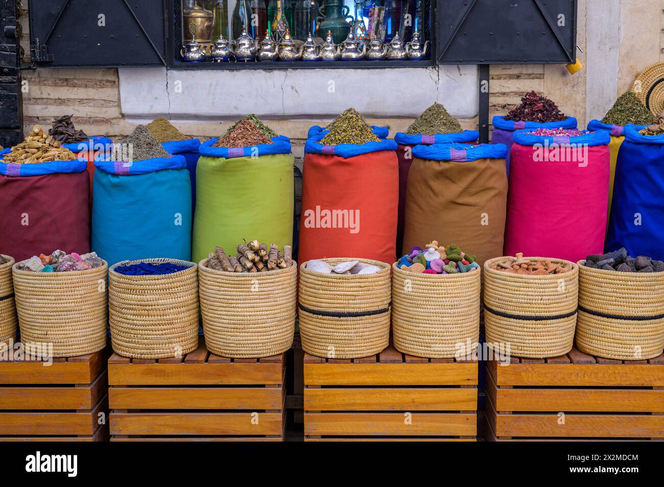 Colorful sacks of aromatic spices and traditional woven baskets showcased in a Moroccan market, reflecting the rich culinary culture. Stock Photo