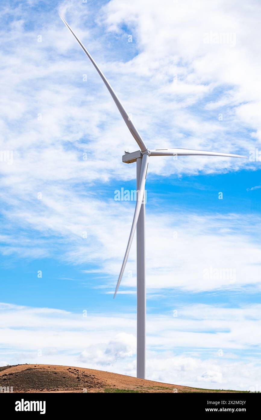 Modern wind turbine standing tall on a barren hill under a sky with ...