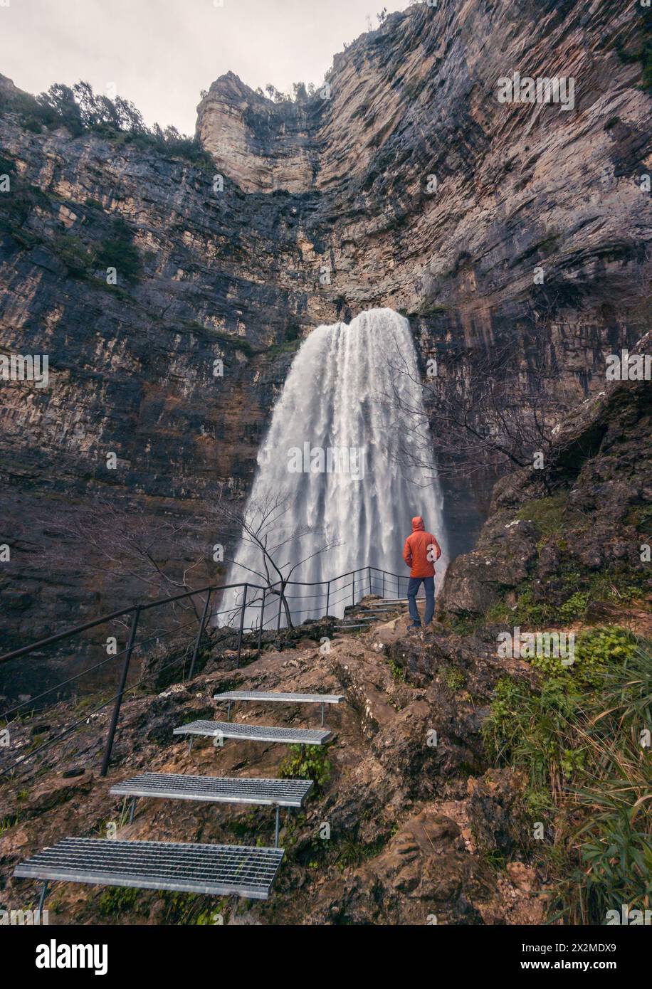 A person in orange observes the majestic Reventón waterfall at Rio Mundo's source Stock Photo