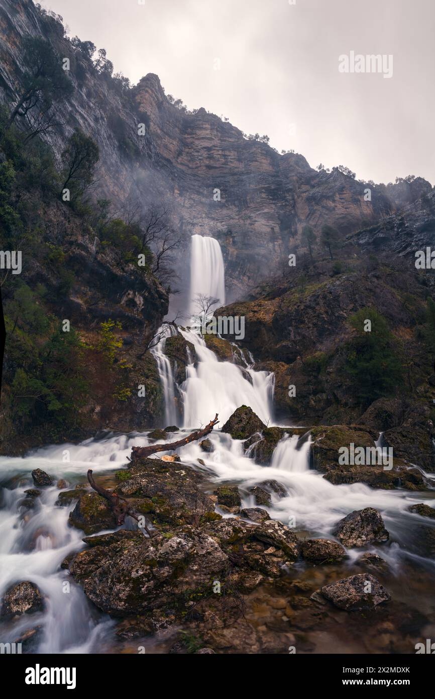 The Reventón del Rio Mundo dramatically cascades down a rocky cliff surrounded by lush foliage, showcasing the natural beauty of Castile-La Mancha Stock Photo