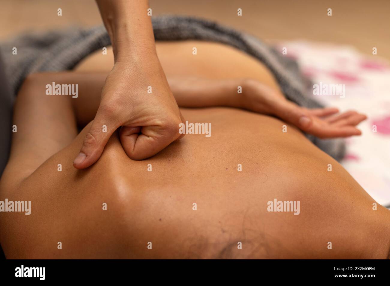 Latina woman lying on her back receiving an ayurvedic back massage treatment Stock Photo